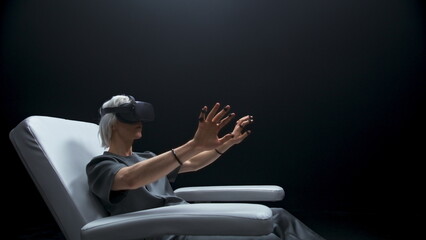 Amazed guy sensor gloves sitting armchair. Future device man watching 3d movie