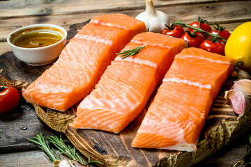 Raw salmon fish filet with lemon, tomatoes and herbs.