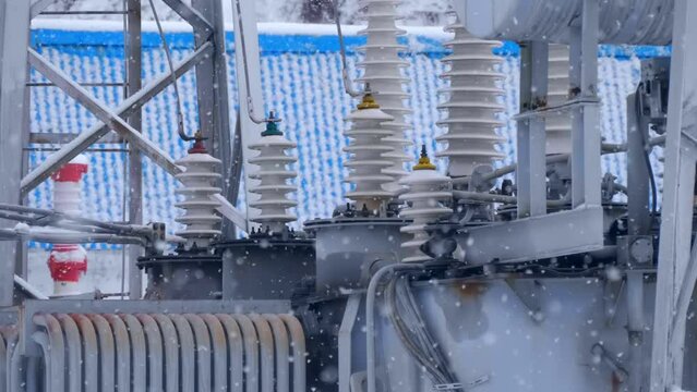 Transformer substation with wires, insulators, electric busbars, power transformer, switchgears, switching equipment in winter during snowfall