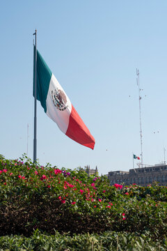 Mexican flag waving with blue sky and the government building of Mexico City  in Mexico City