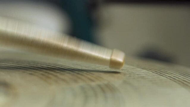 White drum stick hitting a golden ride cymbal in a constant pattern. Professional music instrument drum kit.