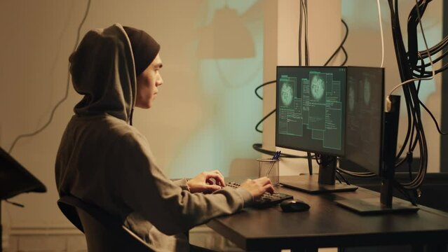 Young hacker enjoying cybercrime achievement at night, breaking into security system to steal data. Male thief planning espionage and hacktivism, applauding and clapping hands.