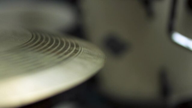 Close up with shallow deph of field of white vintage drum stick hitting professional yellow golden ride cymbal in slow motion