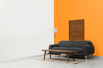 Stylish room with cosy sofa near orange wall. Interior design