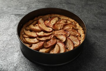 Delicious apple pie in baking dish on grey table