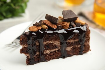 Piece of tasty homemade chocolate cake with nuts on plate, closeup