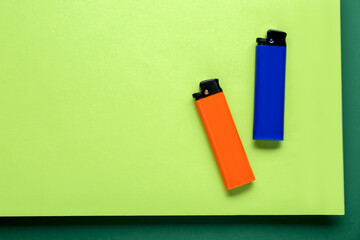 Stylish small pocket lighters on color background, flat lay. Space for text