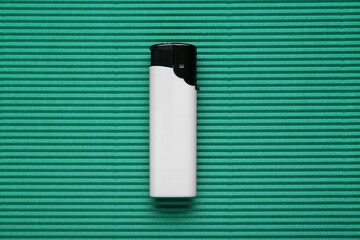 Stylish small pocket lighter on green corrugated fiberboard, top view - obrazy, fototapety, plakaty