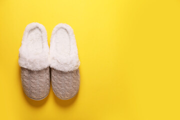 Pair of beautiful soft slippers on yellow background, top view. Space for text