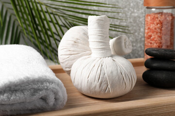 Fototapeta na wymiar Herbal massage bags, rolled towel, spa stones and sea salt on wooden tray, closeup
