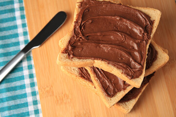 Tasty toasts with chocolate paste on wooden board, space for text