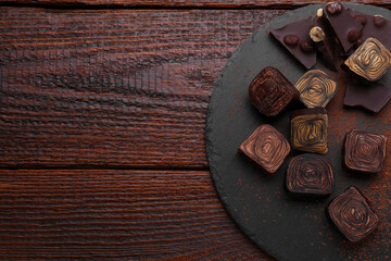 Different tasty chocolate candies on wooden table, flat lay. Space for text