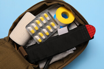 Military first aid kit on light blue background, top view