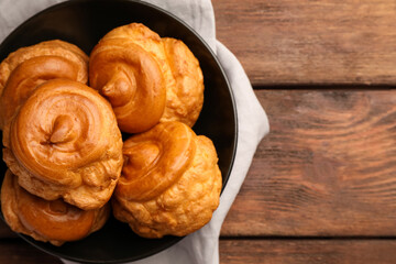 Plate with delicious profiteroles on wooden table, top view. Space for text