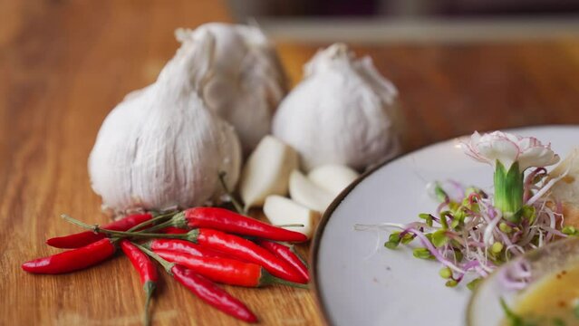 Whole head of garlic and small red chili peppers. Restaurant cuisine concept. Closeup shot. Indoor. High quality 4k footage