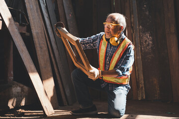 An elderly carpenter works the wood with meticulous care.