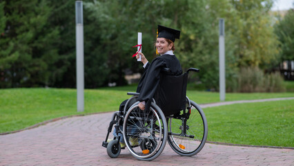 Happy caucasian woman in a wheelchair turns around and holds her diploma outdoors.