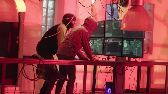 Mysterious hackers being scared of police lights and law enforcement signals, risking to get caught with cybercrimes and espionage. Team of spies stealing government data. Tripod shot.