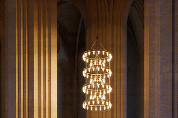 Dark atmosphere and selective detail of lamp chandelier, cream brick vault, arch, rib wall, column...