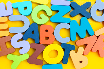 Colorful wooden alphabets on yellow background.
