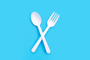 Plastic fork and spoon on blue background.