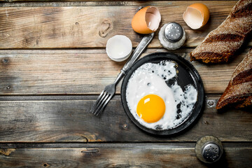 Fried egg in a pan with rye bread.