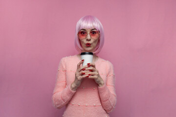 young surprised girl with pink hair holding coffee on pink background