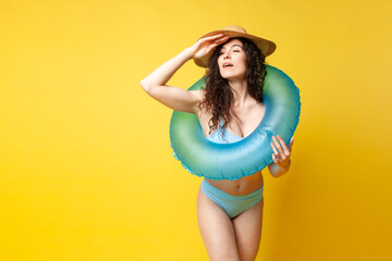 young slender brunette girl in a blue swimsuit in summer with an inflatable swimming ring looks far away