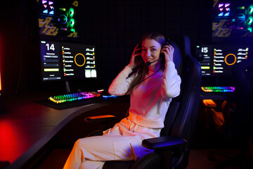 girl gamer sits in headphones in a computer club looks at the camera and smiles, portrait of a...