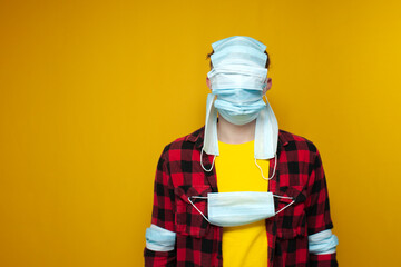 young guy in closed medical masks, a lot of covid masks on the guy's face and head, pandemic stress