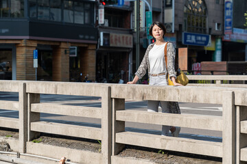 portrait of a Asian beautiful short haircut woman standing alone in city outdoors bridge look in...