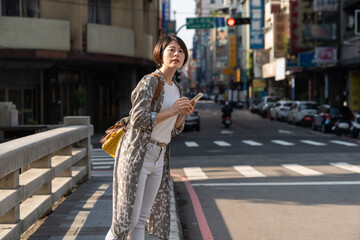 Young smiling business office woman catching taxi at city street after she booking the taxing...