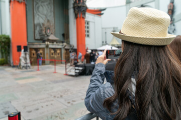 young asian girl making photo with cell phone during travel on Hollywood