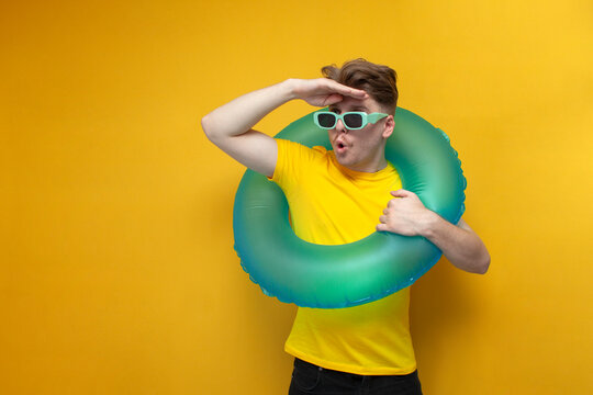 guy in summer clothes with a swimming inflatable ring looks into the distance, the concept of traveling to the sea