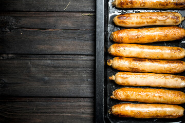 Fried sausages on a baking sheet.