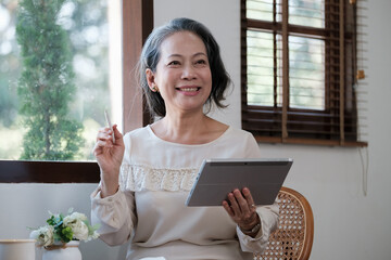 Smart asian mature middle-aged businesswoman CEO boss leader teacher using tablet, e-learning,...