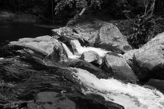 Corredeira na Cachoeira do Paquetá - ILHABELA, SP, BRAZIL - NOVEMBER 28, 2022: Rapids at the exit of the Paqueta waterfall winding through the rocks, photographed in black and white.