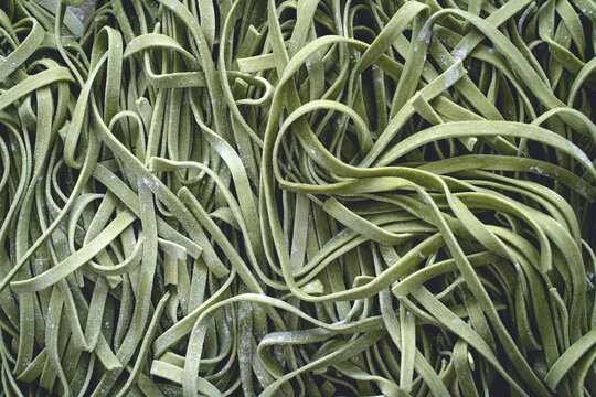 Fresh pasta. Homemade italian raw fettuccine pasta with spinach on wooden table background