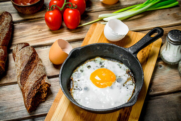 Fried egg in a pan with bread, tomatoes and green onions.