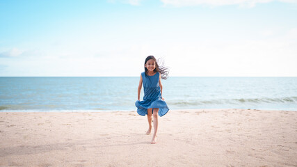 Happy and healthy asian little girl is running on the beach with happy moment for holiday vacation time. Concept of travel, nature, outdoor activity for kid.