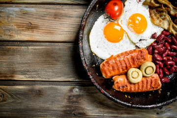 English breakfast. Fried eggs with tomatoes, sausages and beans.
