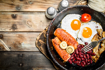 English breakfast. Fried eggs with tomatoes, sausages and beans.