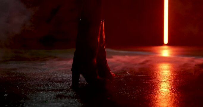 woman standing in boots on wet and foggy street in slow-motion.