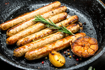 Fried sausages on a pan with herbs and spices.