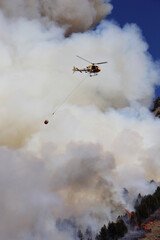 helicopter fire fighting with bucket in mountain wildfire