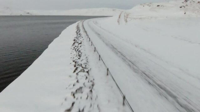 Snowy country road along ocean shore, dolly forward