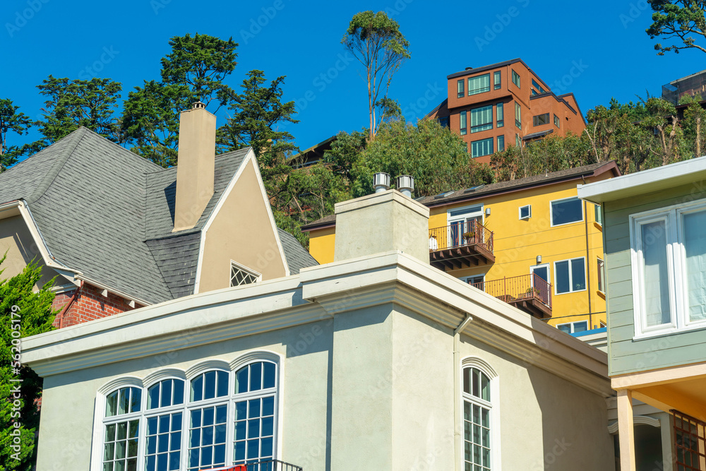 Wall mural row of decorative houses red beige white and blue facades with blue sky and visible trees in afterno