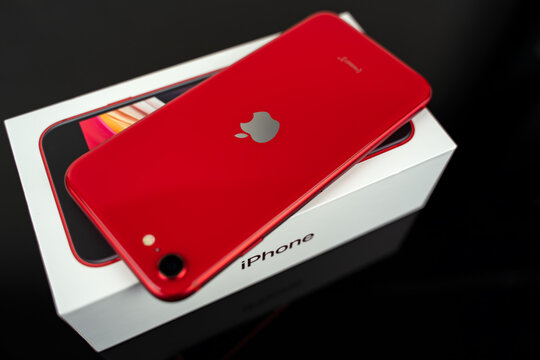 Red iPhone SE with box.