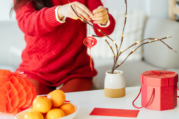 Asian Woman decorated house for Chinese New Year Celebrations. putting traditional pendant to the Chinese Lunar New Year for good luck. Chinese word means blessing