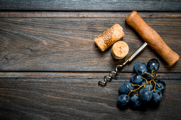 Corkscrew with corks and grapes.